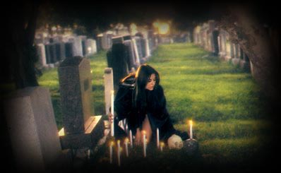 Babetta at graveside with candles performing a ritual